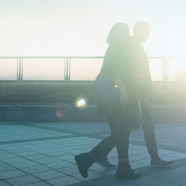 夕暮れ時に歩道を歩く男女